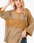 A woman wearing a loose, patchwork-style top with waffle-knit and solid fabric panels in tan and brown tones, featuring a star applique on the chest and a button placket.