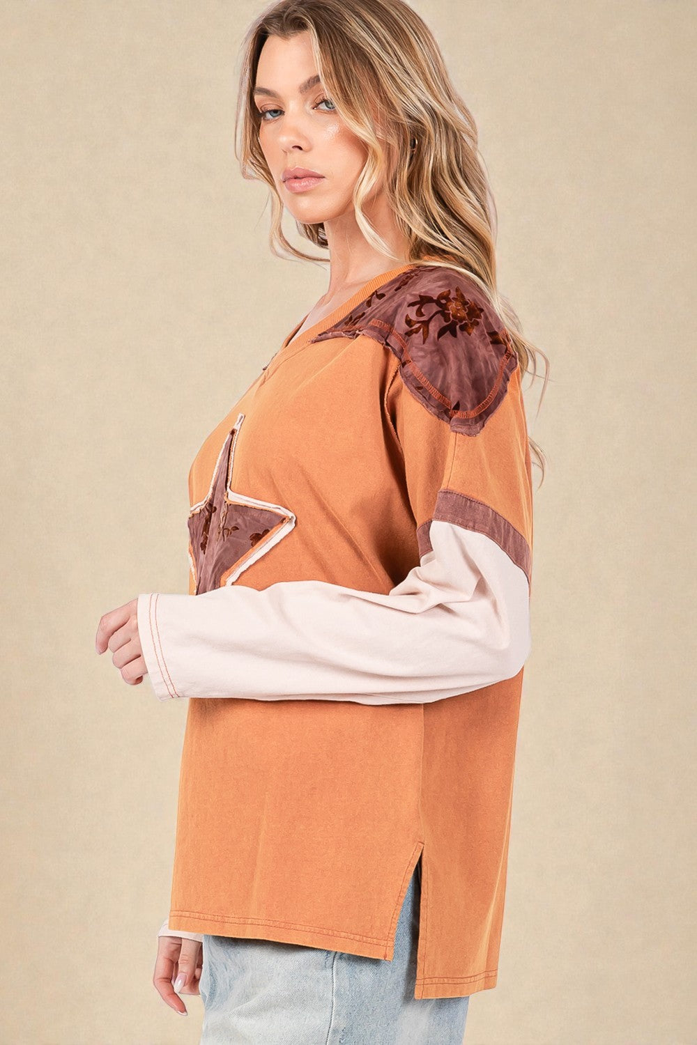 Woman wearing a brown and white top with floral details on a beige background