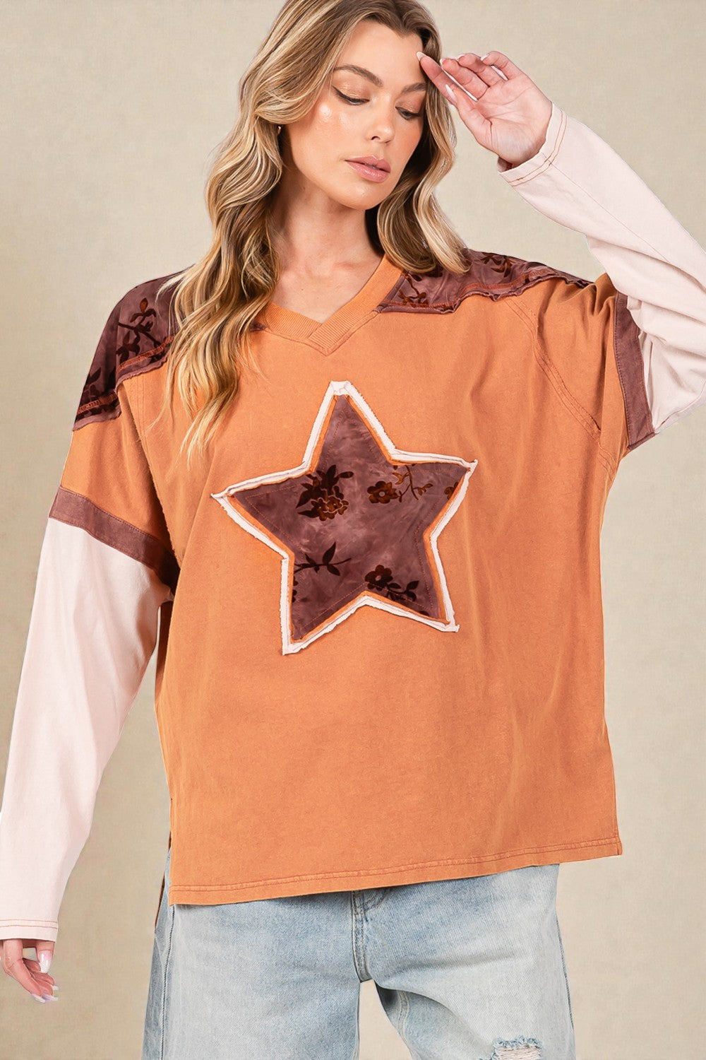 Woman wearing a brown oversized shirt with star design and color-blocked sleeves.