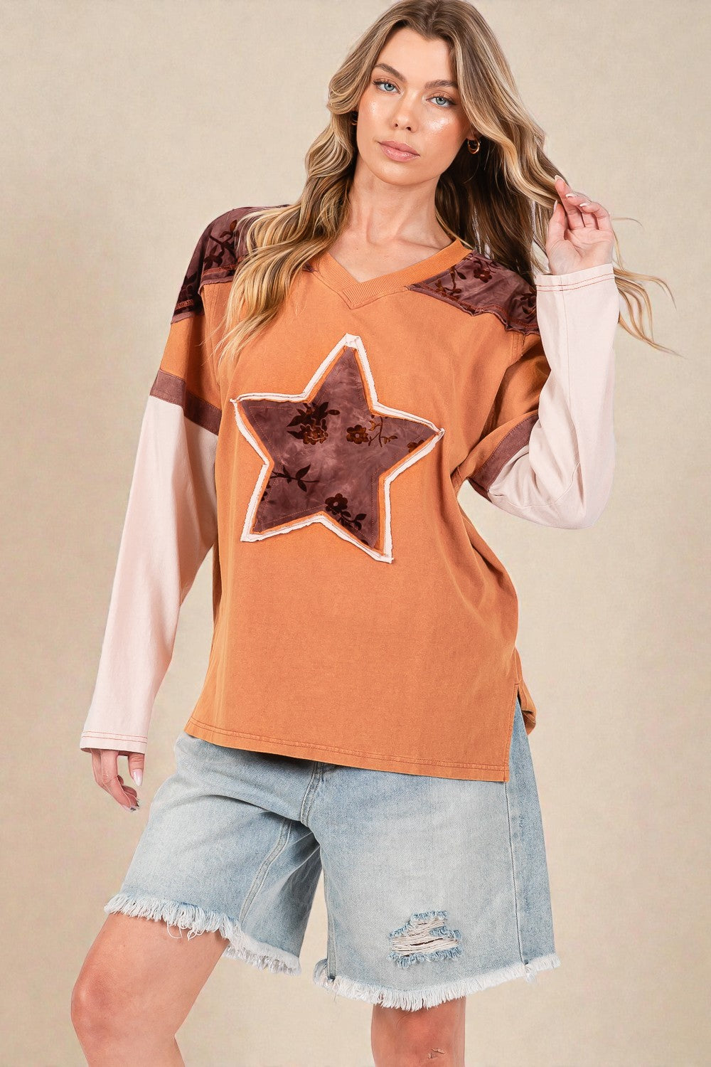 Woman wearing a brown star-patterned top with a beige background