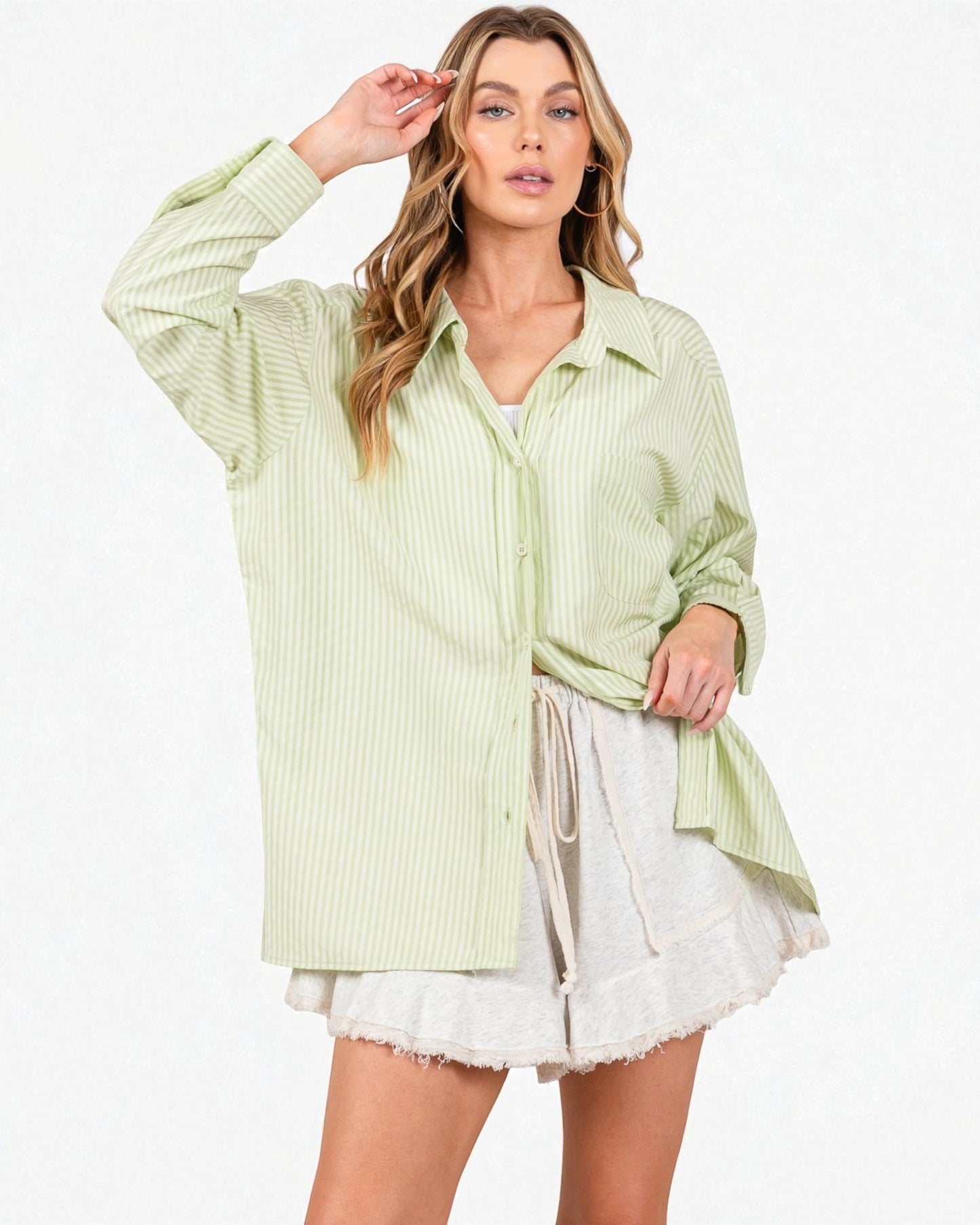 Woman wearing a light green striped shirt over a white lace dress on a white background