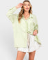 Woman wearing a light green striped shirt and white shorts on a plain background