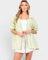 Woman wearing a light green striped shirt over a white top and skirt on a plain background