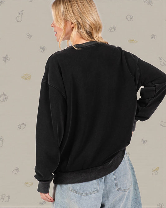 Person wearing a black sweatshirt and light blue jeans against a neutral background