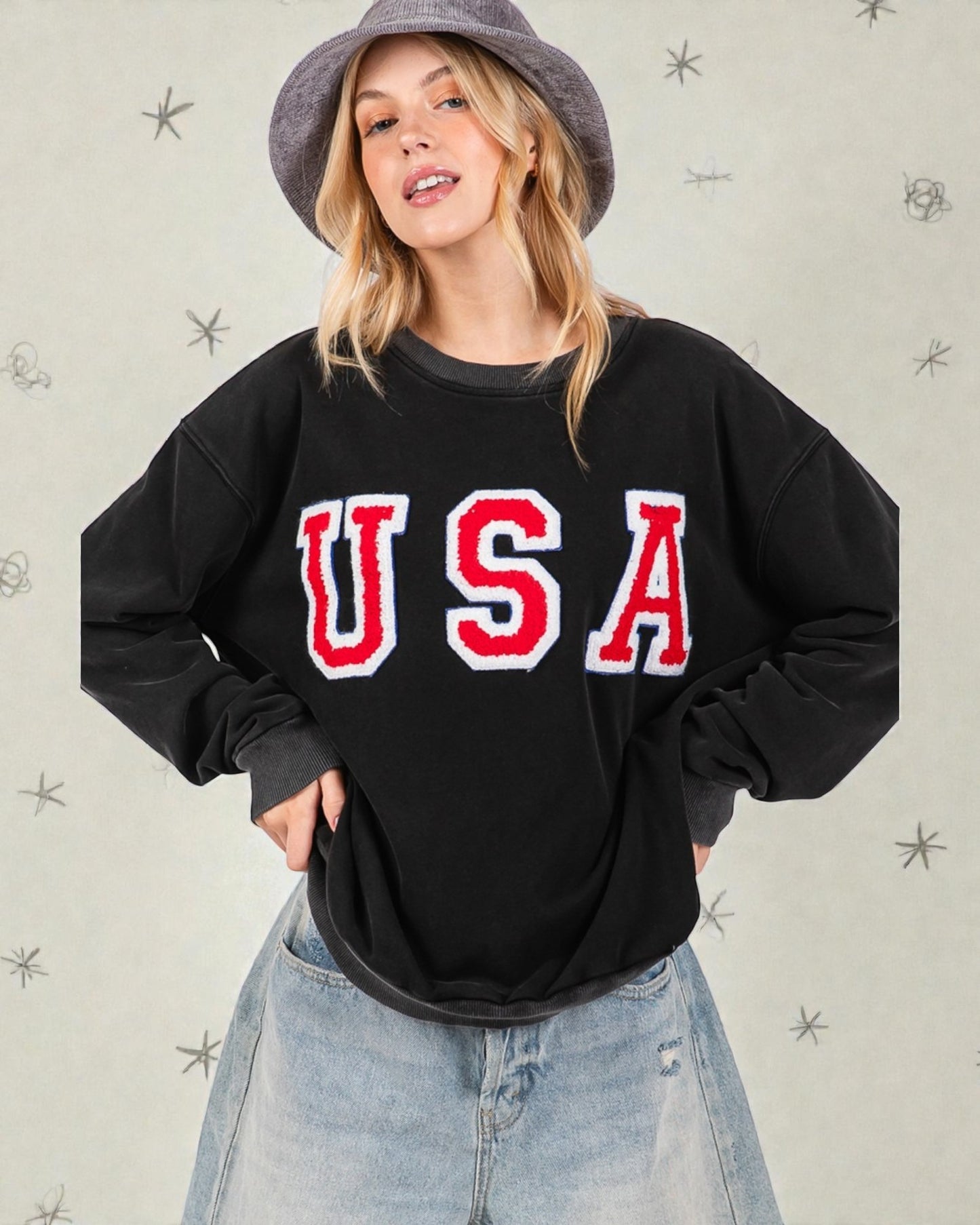 Person wearing a black sweatshirt with 'USA' printed on it against a light background