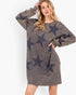 A woman modeling a long-sleeve crewneck sweatshirt dress in a washed charcoal gray color with a dark navy star pattern, set against a plain white background.