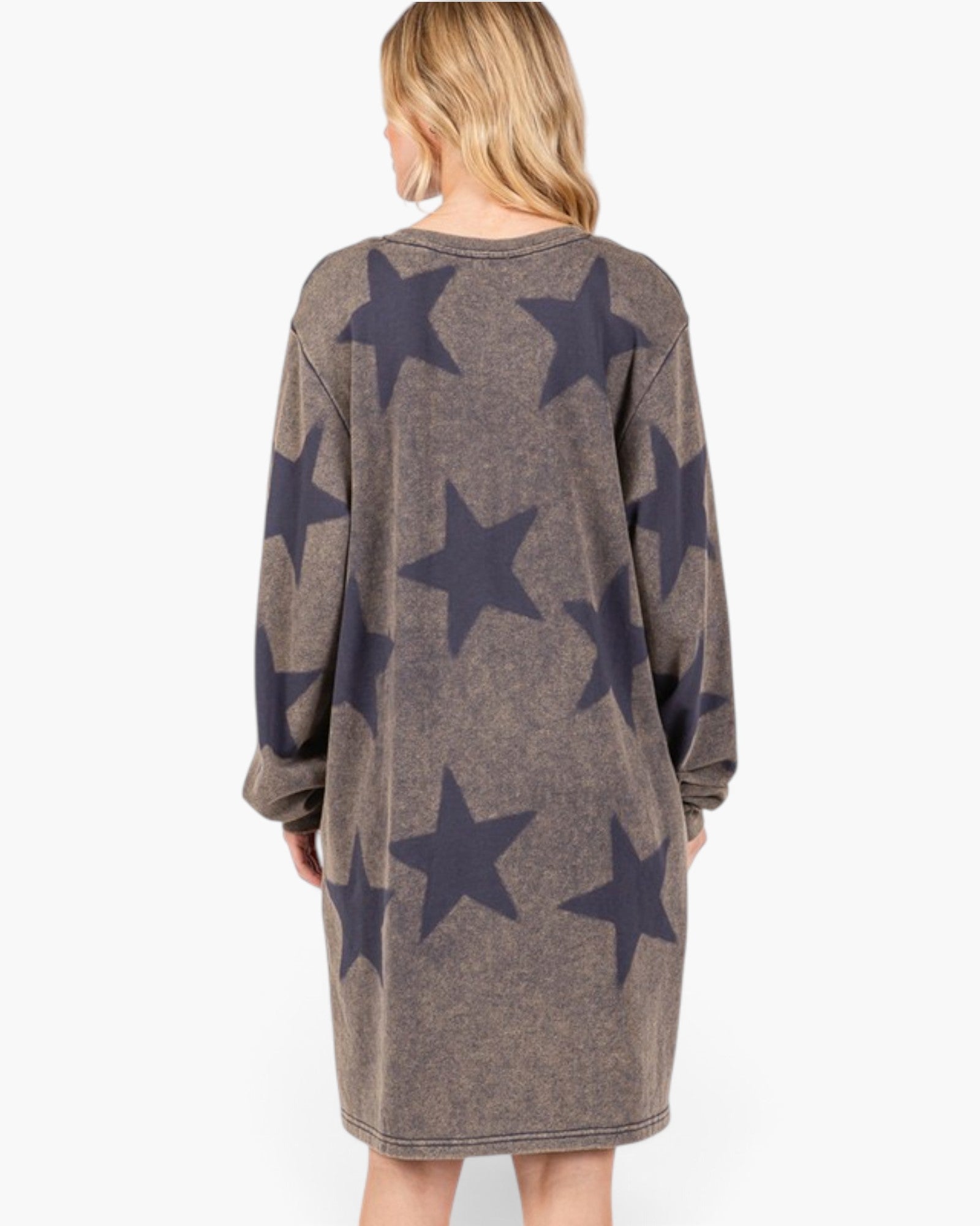 A woman viewed from the back wearing a long-sleeve knit dress with a brown heathered base and large dark navy star pattern, set against a plain white background.