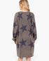 A woman viewed from the back wearing a long-sleeve knit dress with a brown heathered base and large dark navy star pattern, set against a plain white background.