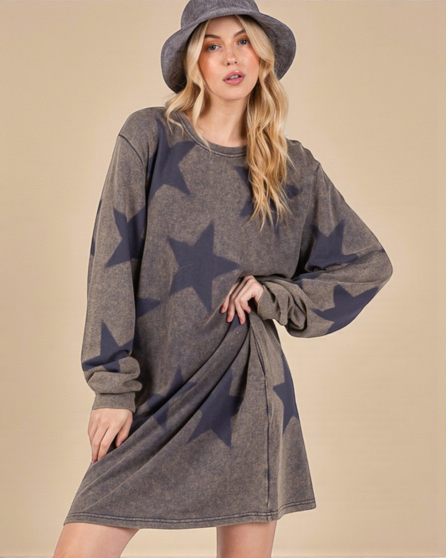 Woman wearing a gray dress with star patterns and a matching hat against a beige background