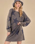 Woman wearing a gray dress with star patterns and a matching hat against a beige background