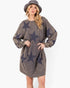 A woman wearing a faded charcoal gray long-sleeve sweatshirt dress with large dark navy star prints, paired with a matching gray bucket hat, against a plain white background.