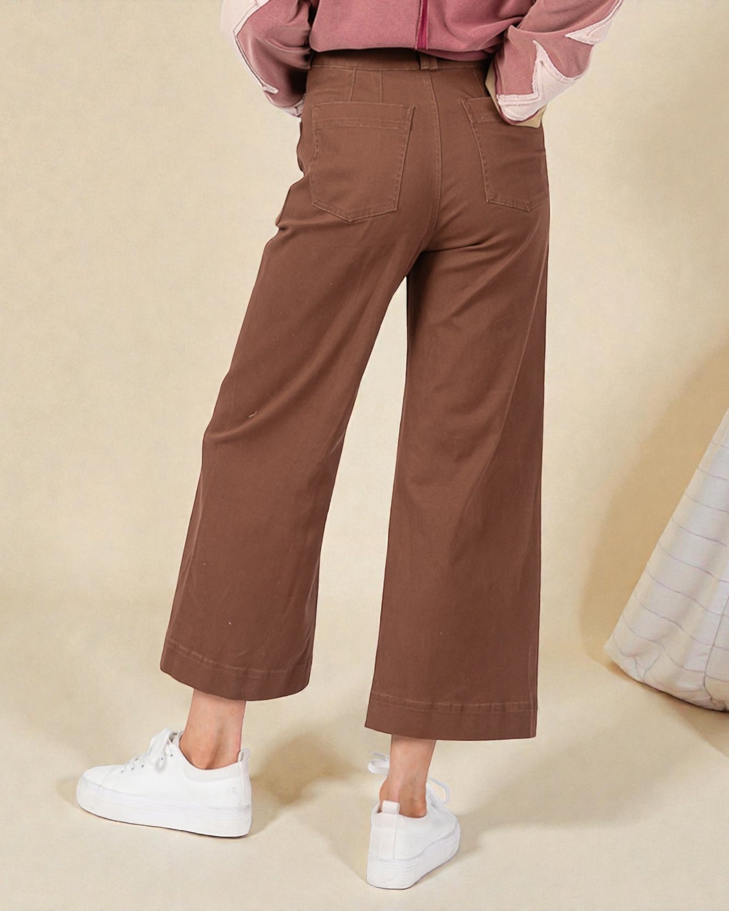 Brown wide-leg pants worn by a person on a beige background