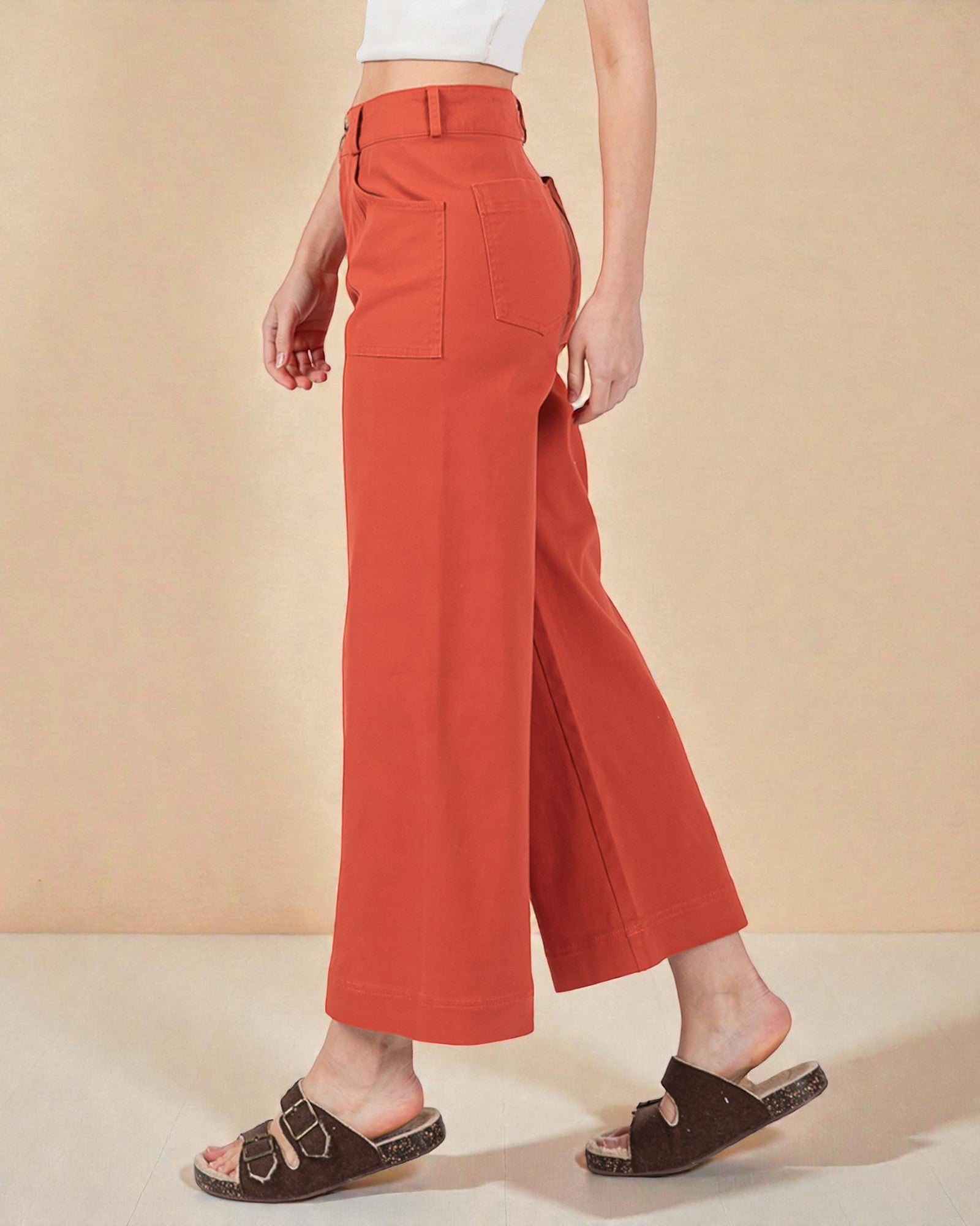 Person wearing orange wide-leg pants on a beige background