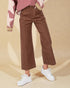 Person wearing brown pants and white sneakers on a beige background