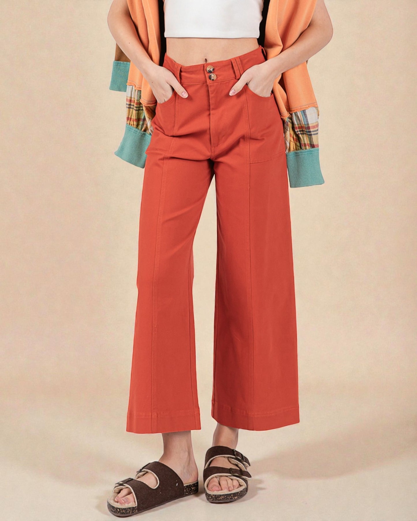 Person wearing orange wide-leg pants with a plain background