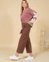 Woman wearing a pink sweater with star patterns and brown pants on a beige background