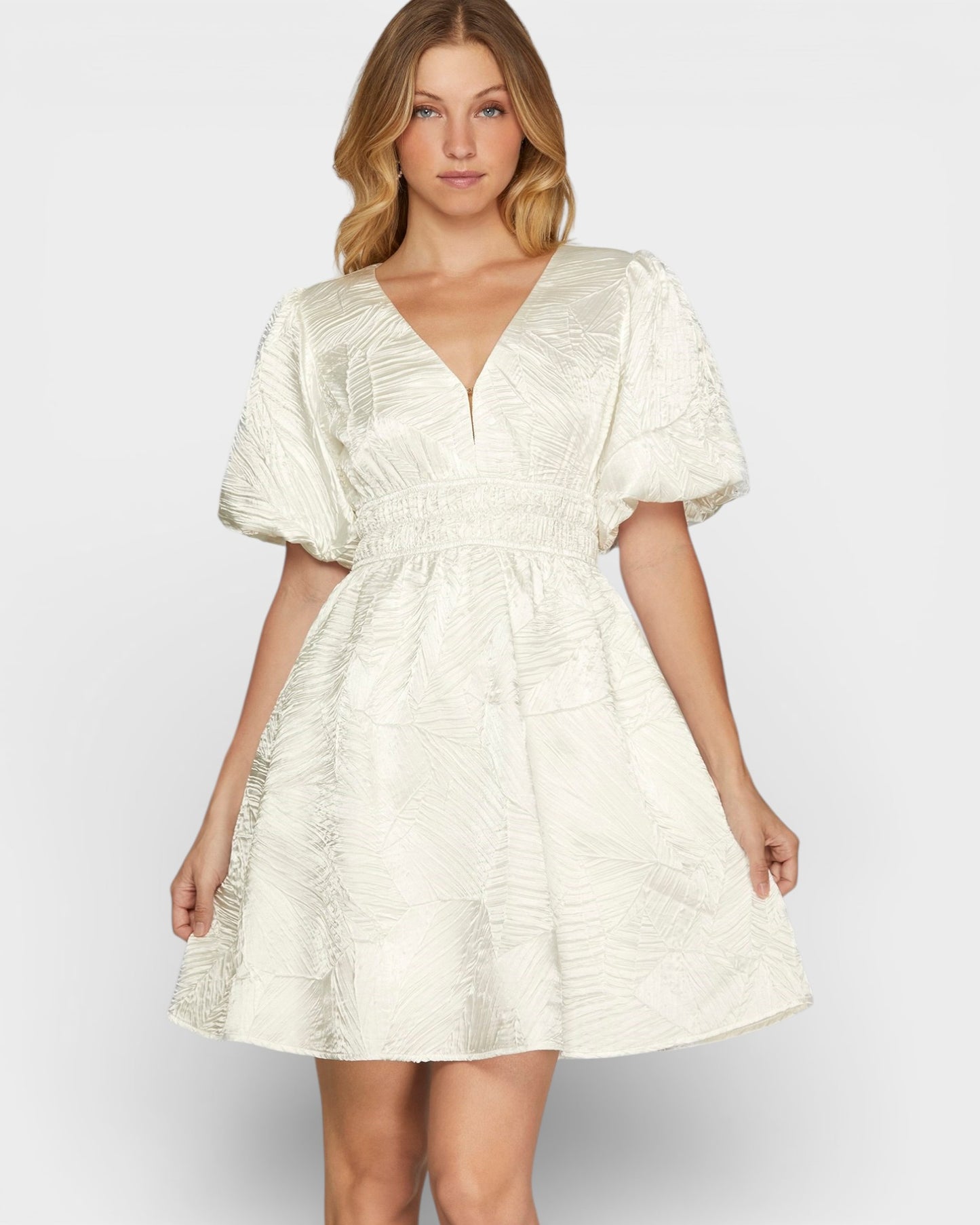 Woman wearing a white patterned dress on a plain background