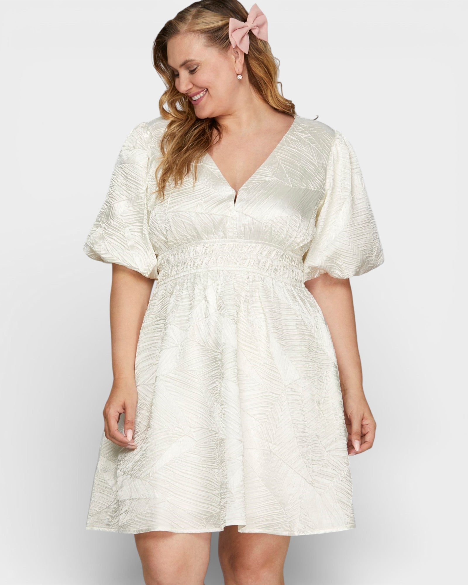 Woman wearing a white dress with puff sleeves against a plain background