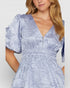 Woman wearing a blue patterned dress on a plain background