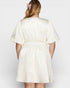 Woman wearing a white textured dress against a plain background