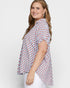 Woman wearing a patterned blouse with a plain background