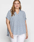 Woman wearing a patterned blue and white shirt against a plain background