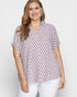 Woman wearing a patterned blouse with a plain background