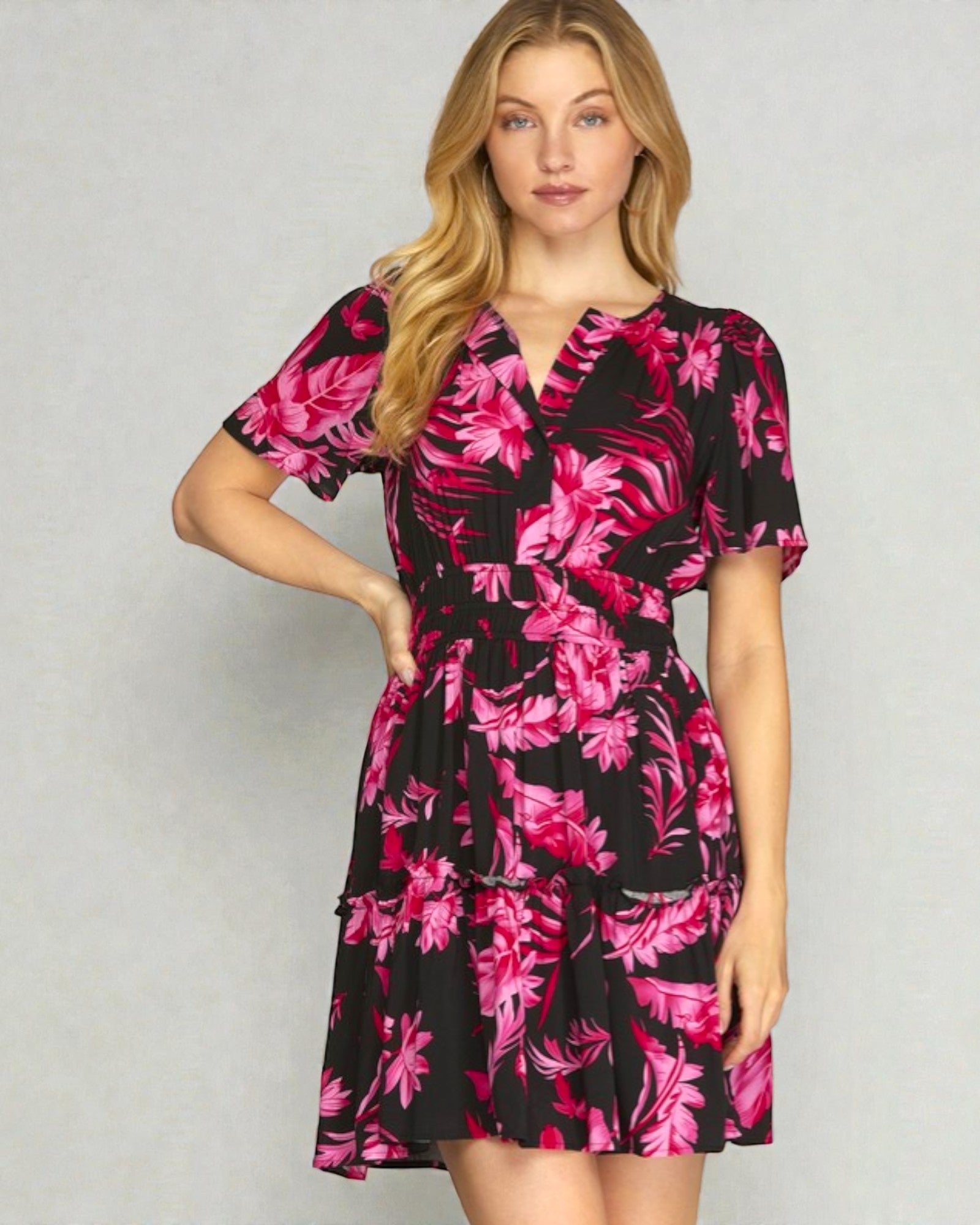 Woman wearing a black dress with pink floral pattern on a gray background