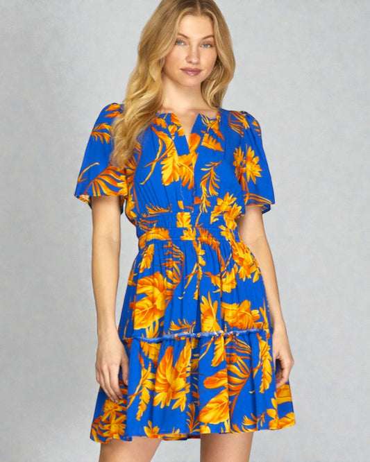 Woman wearing a blue and orange floral dress on a gray background