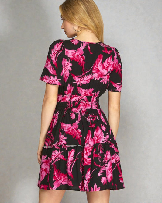 Woman wearing a black dress with pink floral pattern against a gray background