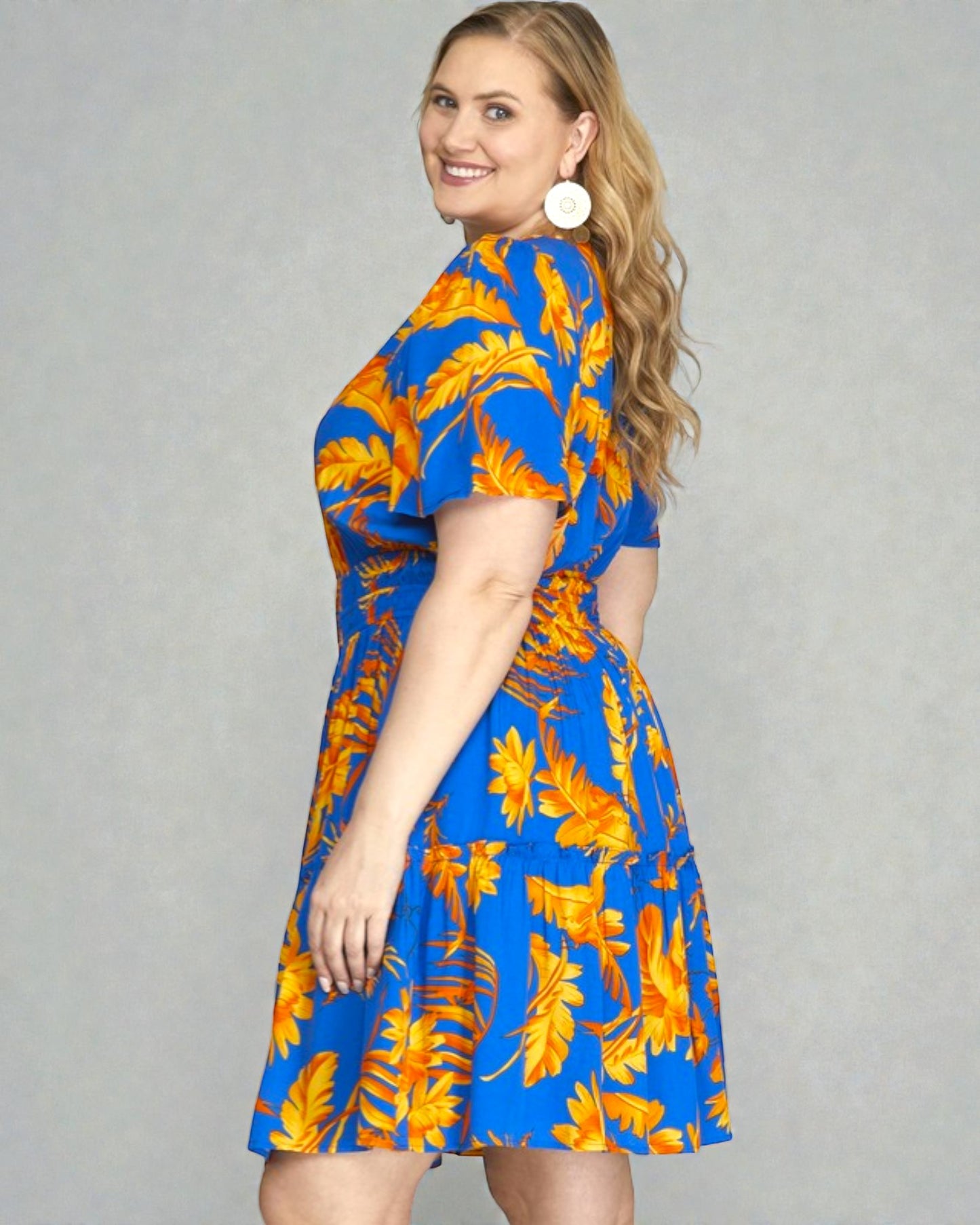 Woman wearing a blue dress with orange floral pattern on a gray background