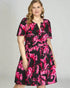 Woman wearing a black dress with pink floral pattern on a plain background