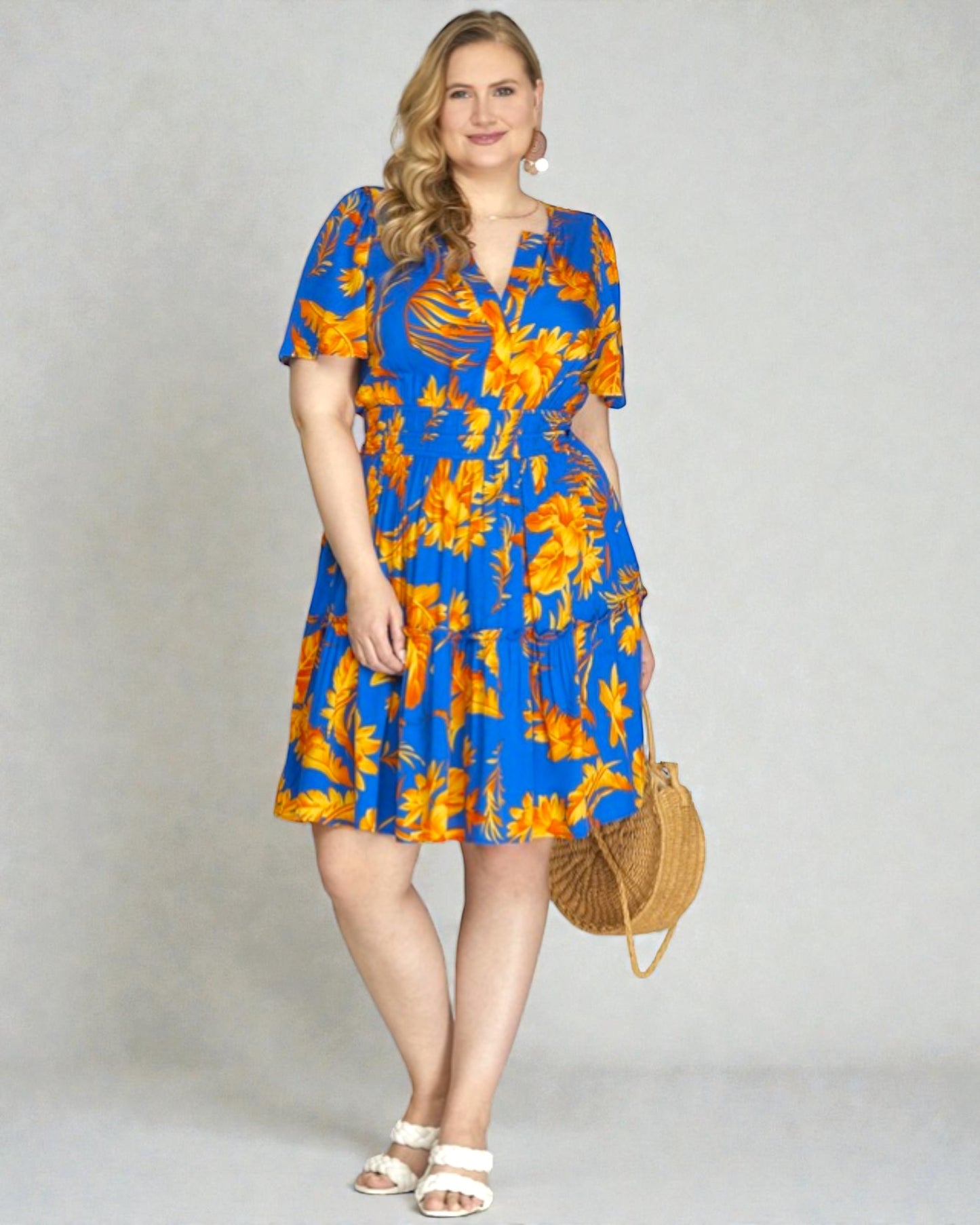 Woman wearing a blue and orange floral dress against a plain background