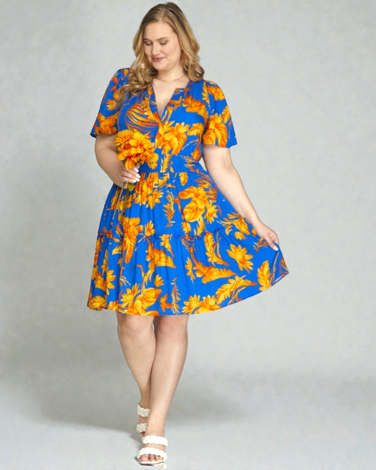 Woman wearing a blue and orange floral dress on a gray background