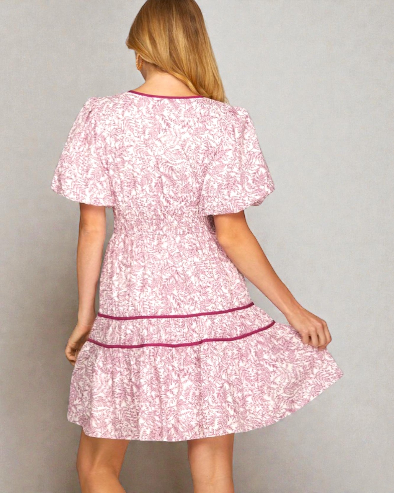 Woman wearing a pink floral dress with a plain background