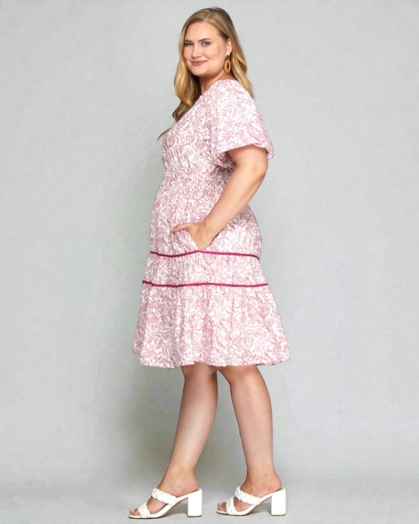 Woman wearing a pink floral dress against a gray background