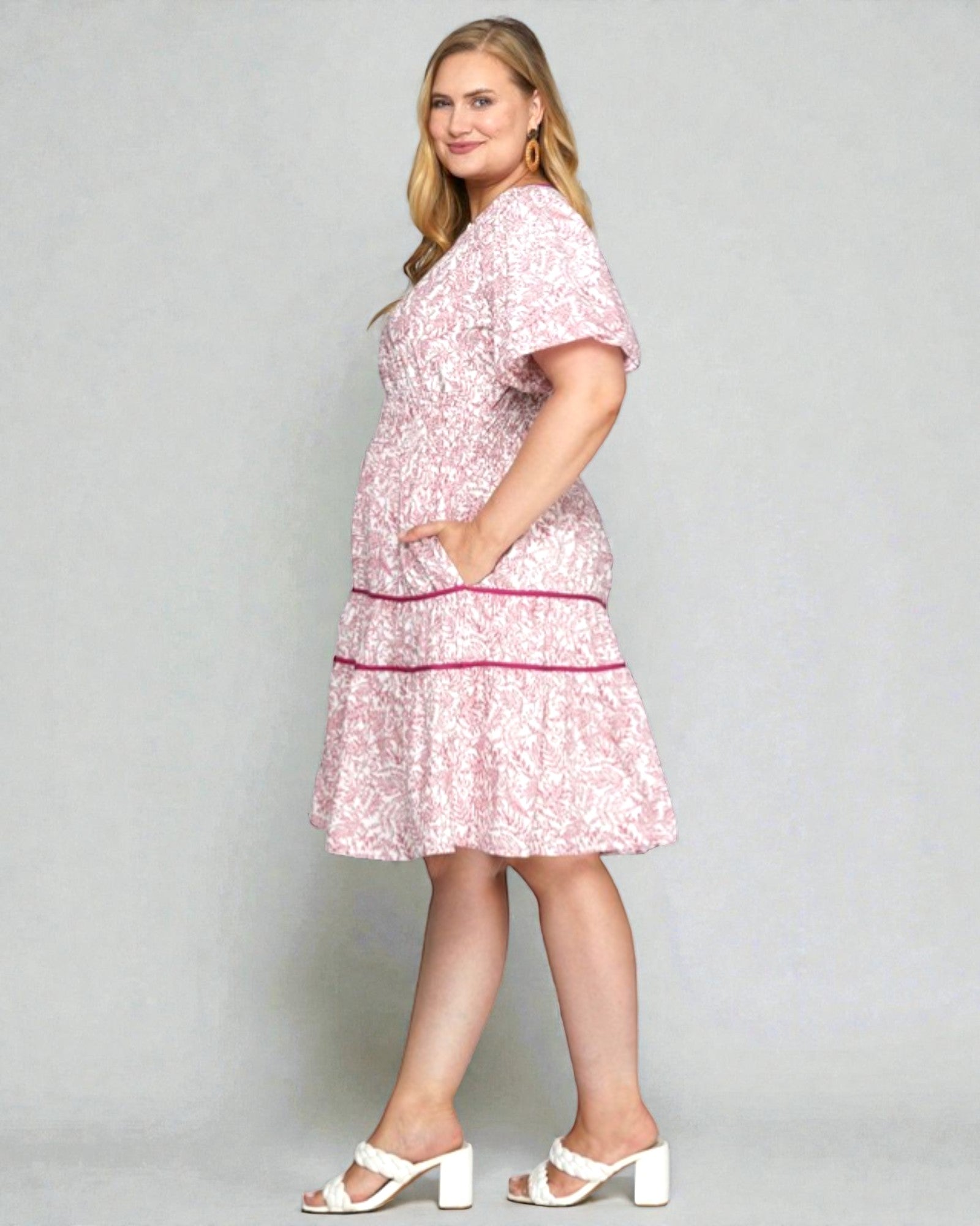 Woman wearing a pink floral dress against a gray background