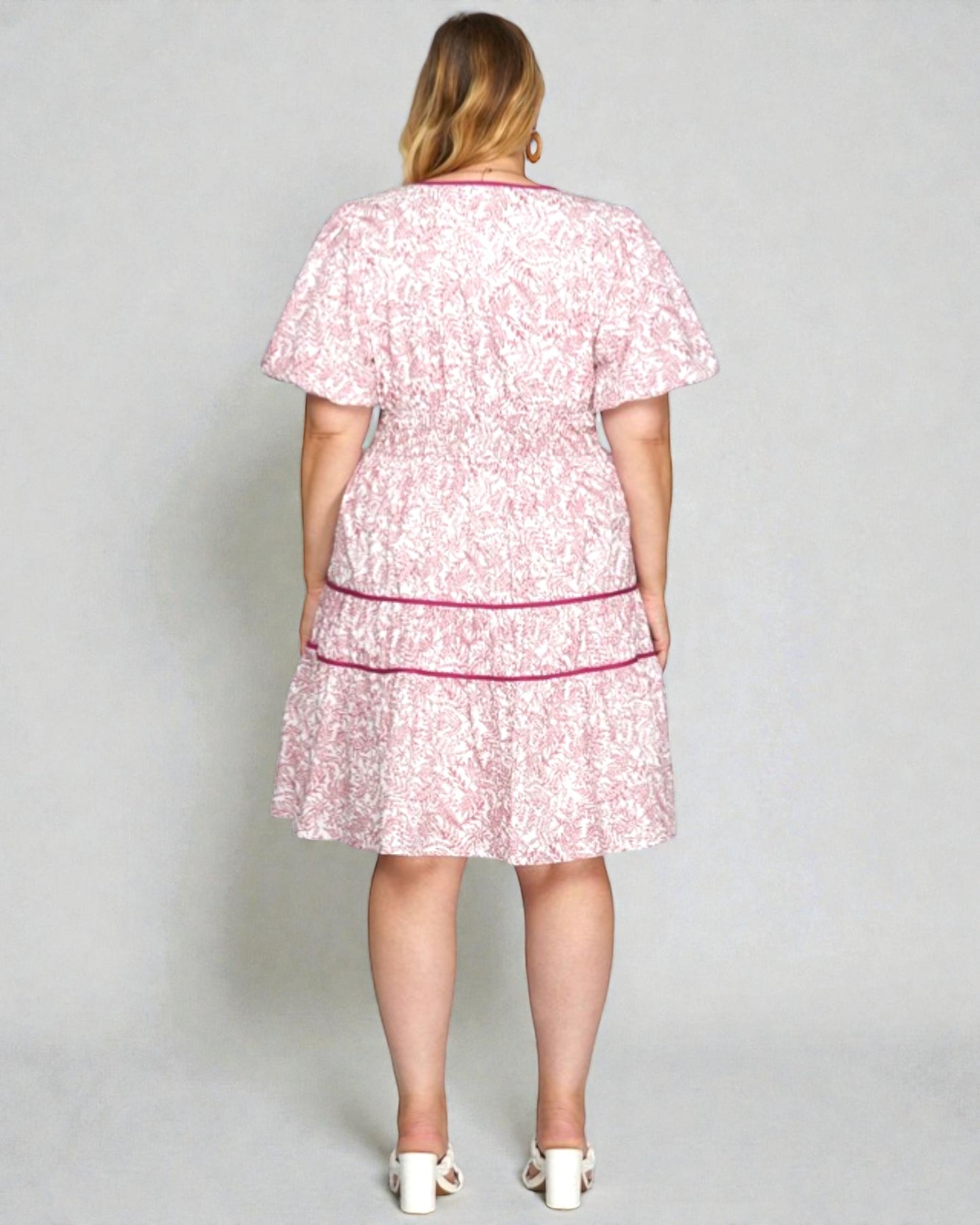 Woman wearing a pink floral dress with a plain background