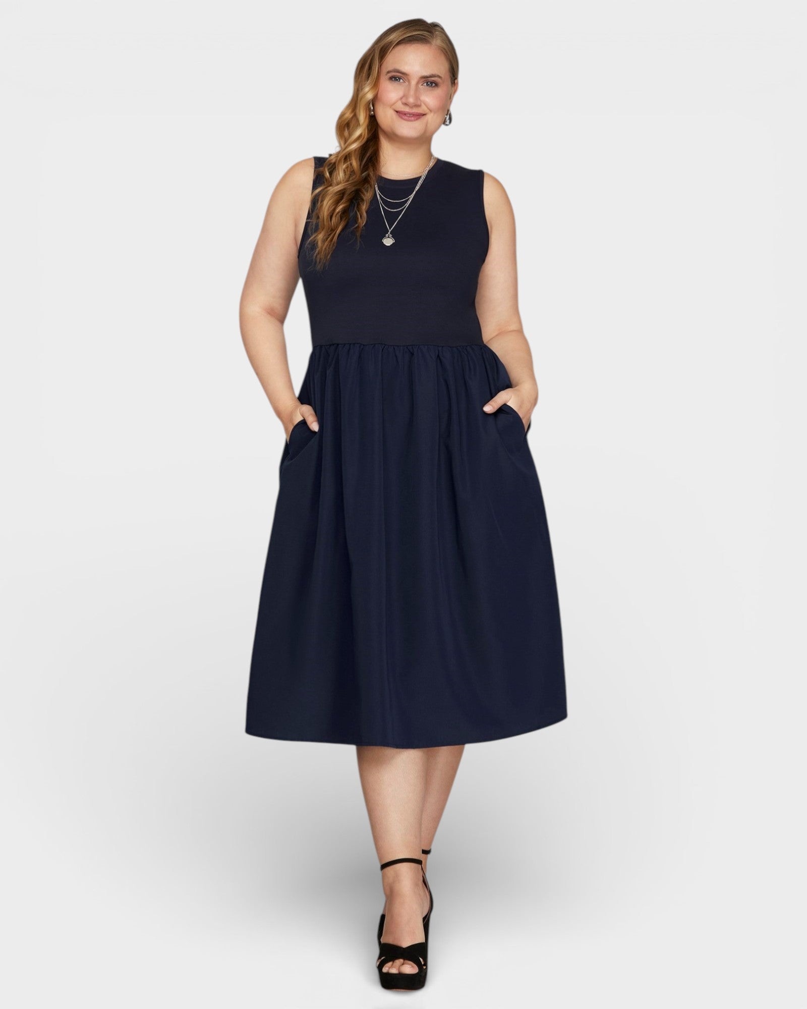 Woman wearing a navy sleeveless dress on a white background