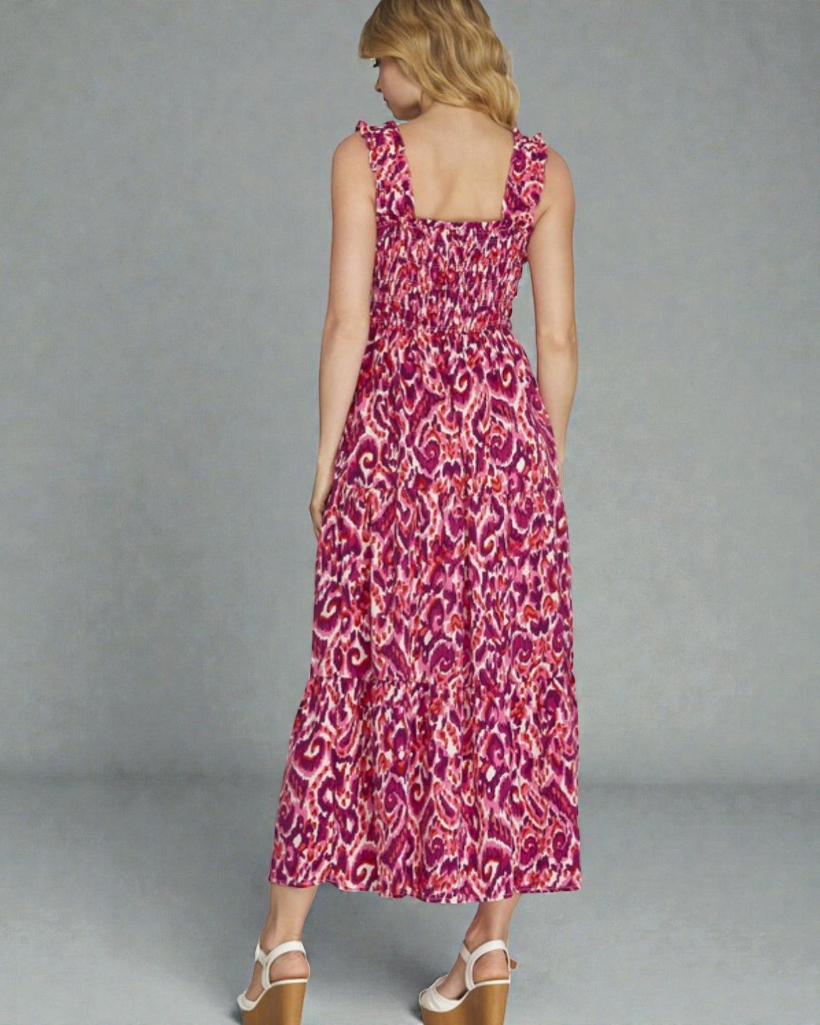 Woman wearing a pink patterned dress against a gray background