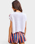 Woman wearing a white top and American flag shorts on a plain background