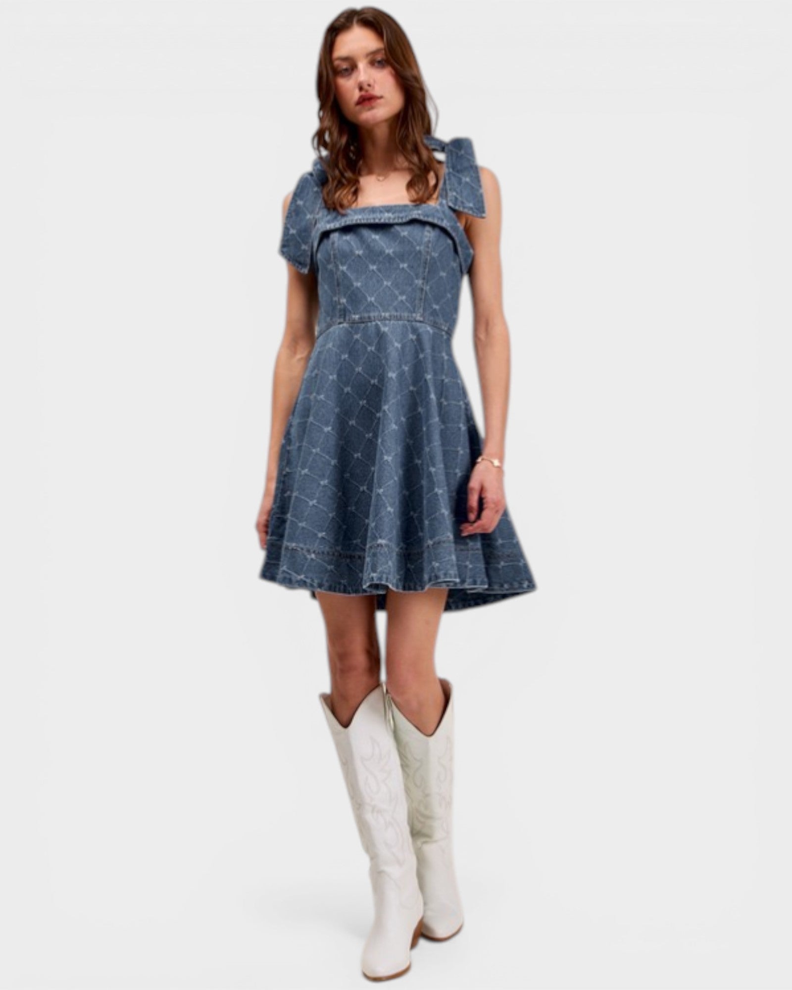 Woman wearing a blue dress with white cowboy boots on a white background