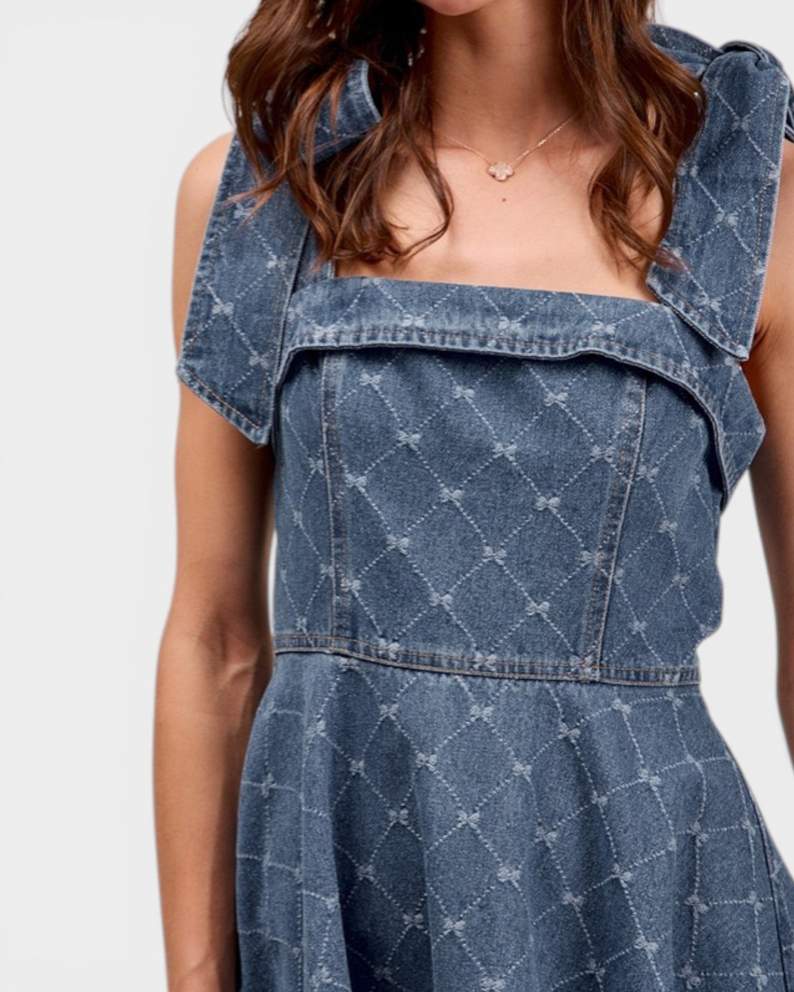 Blue denim dress with ruffled shoulders on a white background