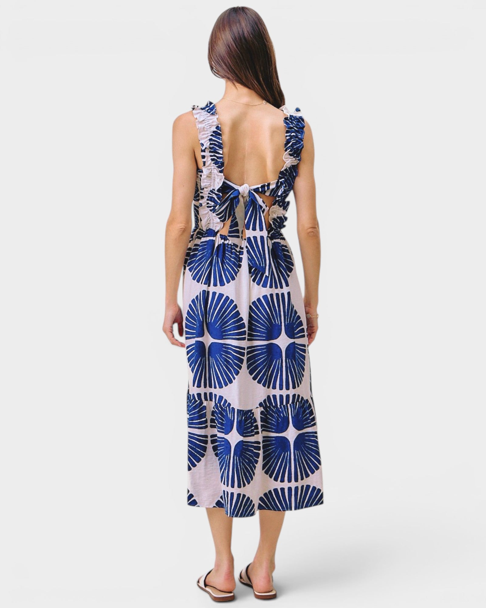 Woman wearing a sleeveless dress with blue floral pattern on a white background