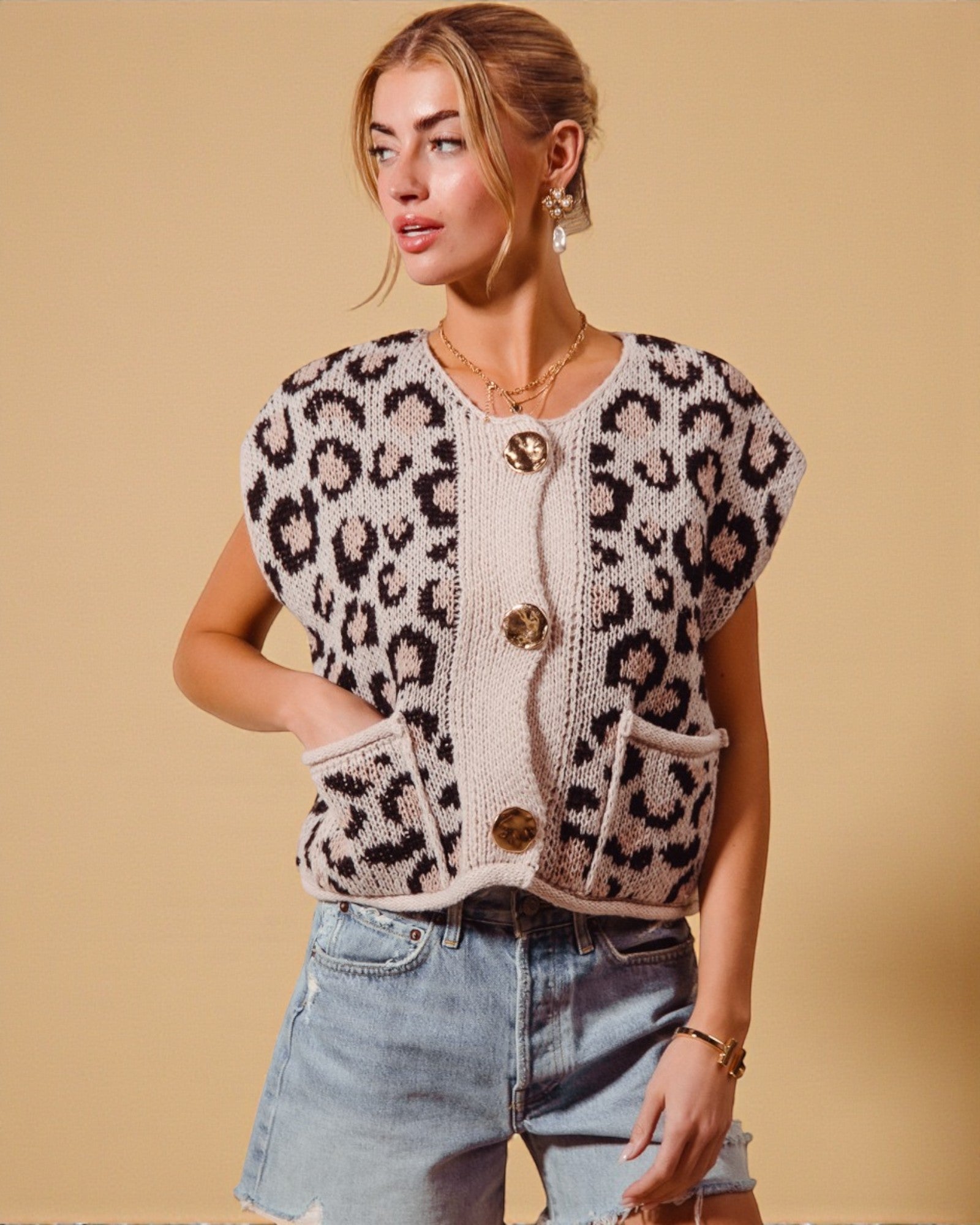 Woman wearing a leopard print cardigan with gold buttons on a beige background