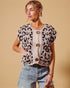 Woman wearing a leopard print cardigan with gold buttons on a beige background