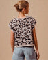 Woman wearing a leopard print top and denim shorts against a beige background