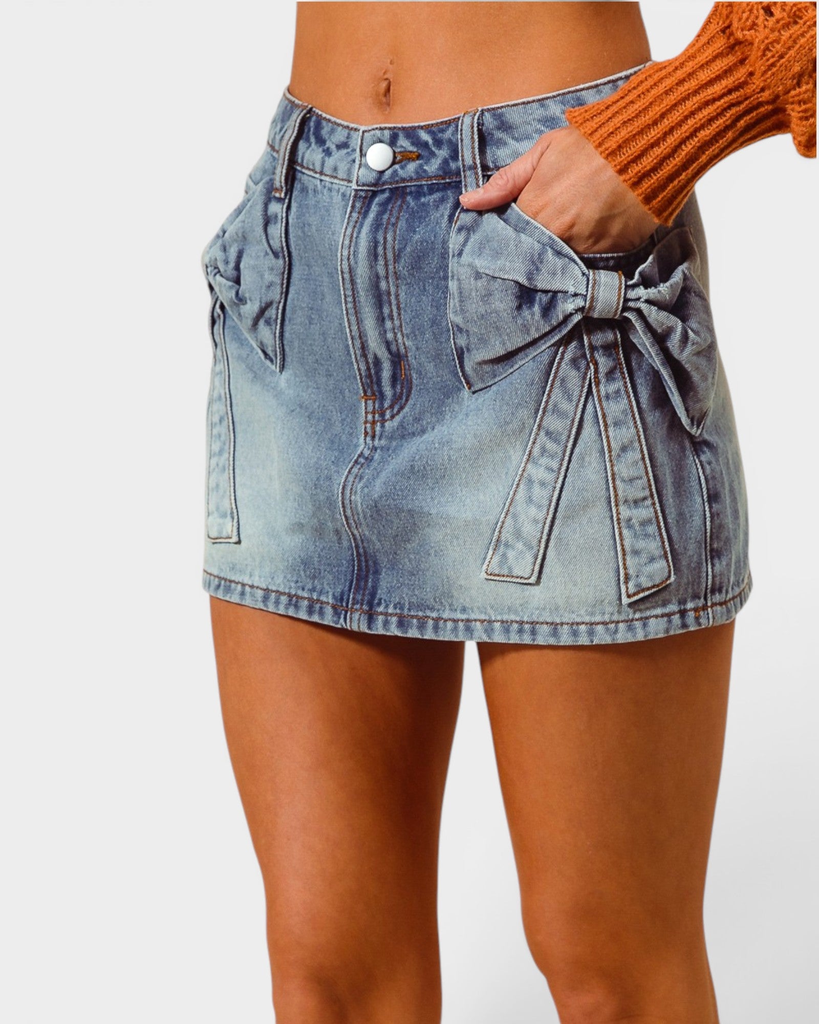 Denim skirt with a bow detail worn by a person on a white background