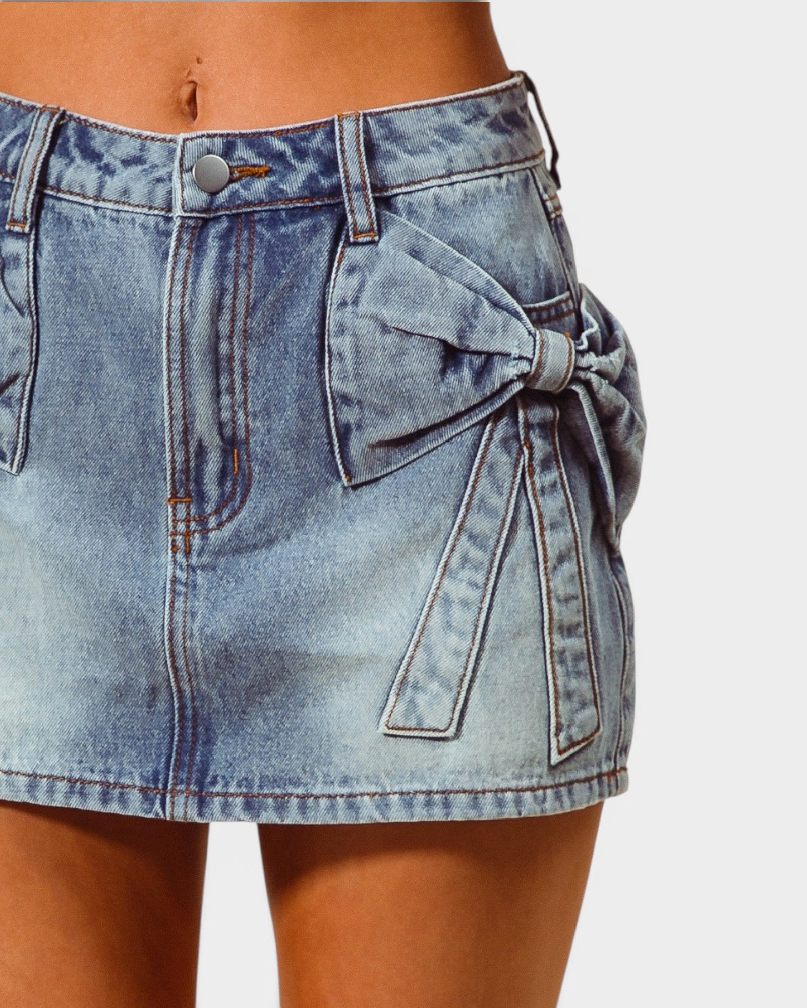 Denim skirt with a bow detail on a plain background