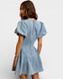 Woman wearing a light blue denim dress on a white background